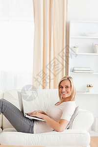 躺在沙发上时 一名携带笔记本电脑的妇女的肖像图片