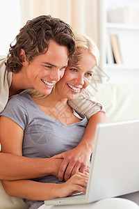使用笔记本电脑的一对年轻夫妇的肖像成人场景安全女性恋人技术女士金发微笑互联网图片