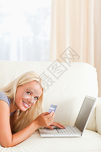 一个微笑的女人在网上购物的肖像笔记本电脑头发卡片互联网金发金发女郎女士工作长椅图片