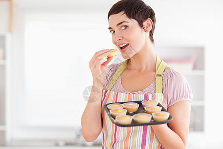 喜悦的黑发女人吃一个时 露着松饼图片