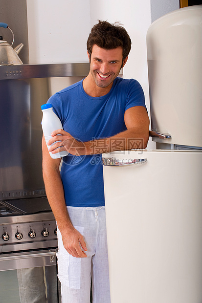 男人在厨房里喝着一瓶牛奶控股家用电器成年人便装食物冰箱饮料瓶子成人微笑图片