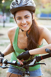 骑自行车的美丽年轻女子安全成人头盔女孩闲暇女性场地微笑街道运动图片