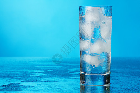 蓝色背景的冰水杯玻璃立方体餐具液体口渴反射白色水晶图片