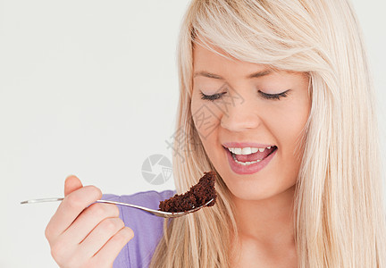 美女金发女人吃蛋糕的肖像背景图片