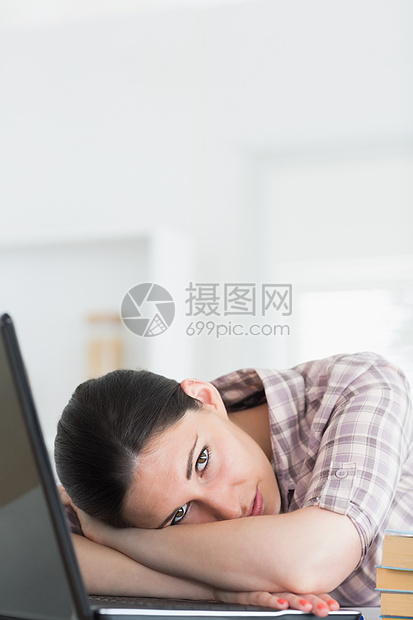 妇女用笔记本电脑靠在桌上图片