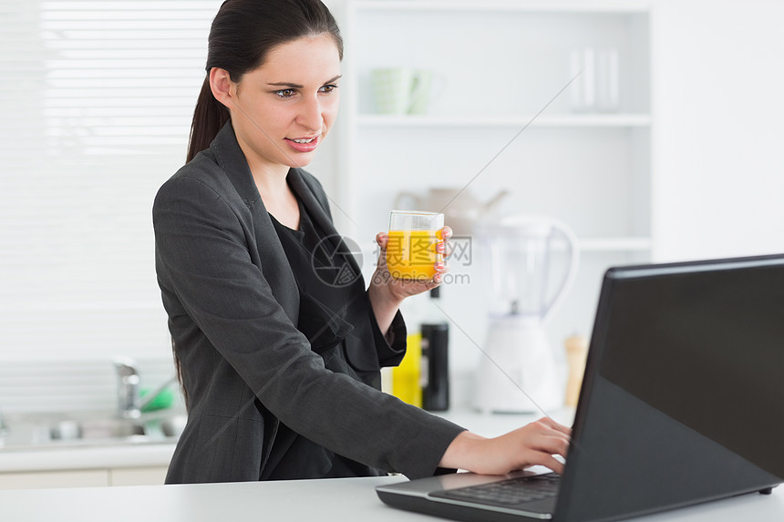 女人拿着果汁杯看笔记本电脑图片