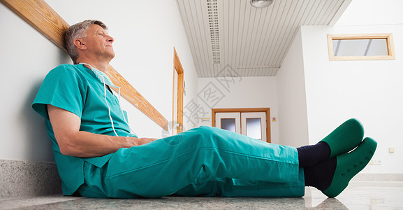 医生坐在地板上职场走廊外科男性制服手术帽男人从业者专家诊所图片