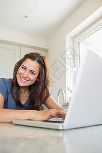 使用笔记本电脑的幸福妇女房子棕色公寓女性家庭女士黑眼睛台面货架桌子图片
