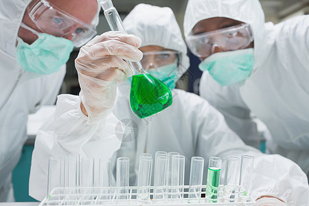 两个化学家在监视下 将绿色液体混合到烧烤瓶中图片