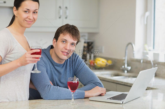 使用笔记本电脑喝红酒的年轻夫妇图片