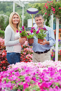 一对夫妇拿着紫色的植物 微笑着图片