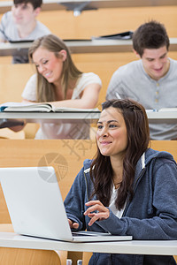 女孩用笔记本电脑坐在教室里女性学习专注报告团体教科书机构男人同学们班级图片