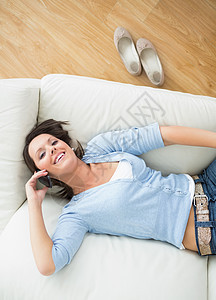 微笑的女人打电话 躺在沙发上图片