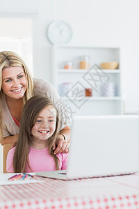 笑着的母亲和女孩看笔记本电脑图片