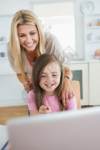 小女孩指着笔记本电脑 跟妈妈一起笑图片