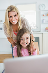 女人和女儿在笔记本电脑上微笑图片