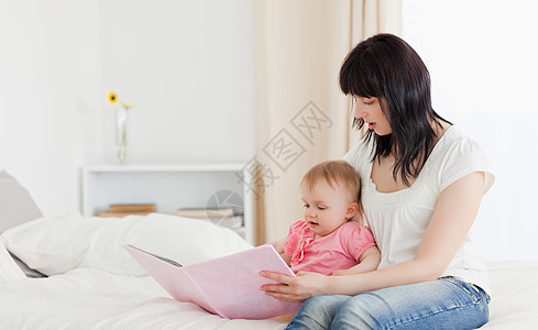 迷人的黑发美女 在坐着时给孩子看一本书图片