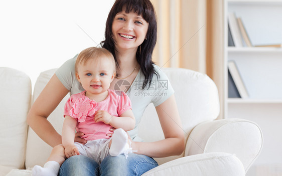 漂亮女人坐在沙发上 抱着婴儿在她的怀里图片