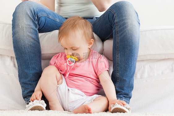 婴儿坐在地毯上玩弄母亲的脚 而婴儿则坐在地毯上图片