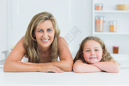 母亲和女儿靠在厨房的桌子上图片