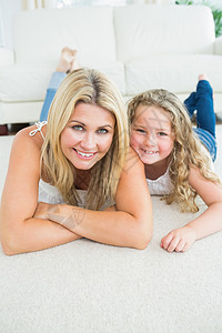 母亲和女儿在地毯上休息长椅头发地面女性女孩客厅沙发浅色木地板微笑图片