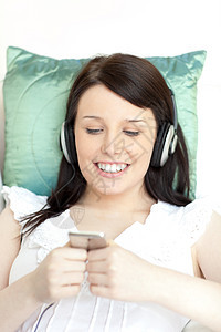 快乐的年轻女子用耳机听音乐青少年休息微笑沙发电话细胞客厅黑发手机成人图片