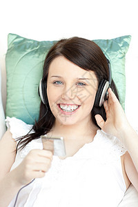 快乐的年轻女士用耳机听音乐沙发成人长椅技术手机细胞女性青少年青年黑发图片