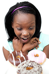 惊讶的年轻女人看甜甜甜圈图片