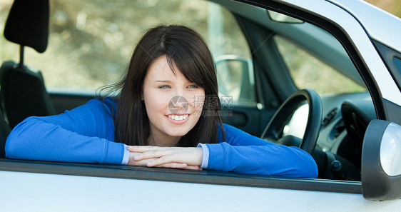 迷人的少女女孩笑着坐在她车里的摄像机图片