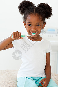 一个微笑的小女孩在刷牙的肖像图片