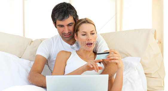 用笔记本电脑躺在床上的爱情侣图片