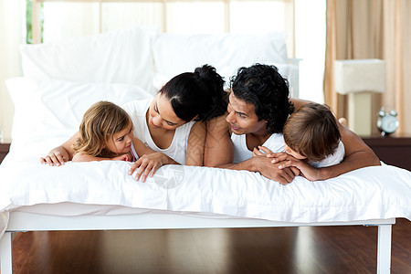 一家人一起在床上放松女孩男生母亲卧室父亲拥抱孩子孩子们感情乐趣图片