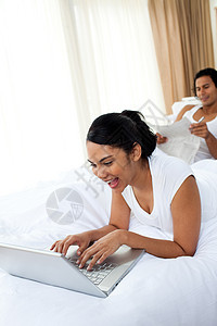 一个女人用笔记本电脑躺在床上图片