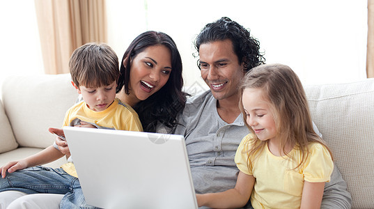 幸福家庭在沙发上使用笔记本电脑夫妻乐趣互联网男人母亲技术女孩冲浪爸爸孩子图片