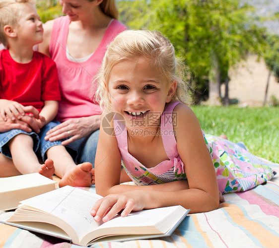 一个小女孩在野餐上看书的近身图片