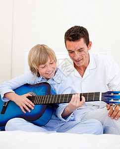 微笑的小男孩和他父亲弹吉他图片