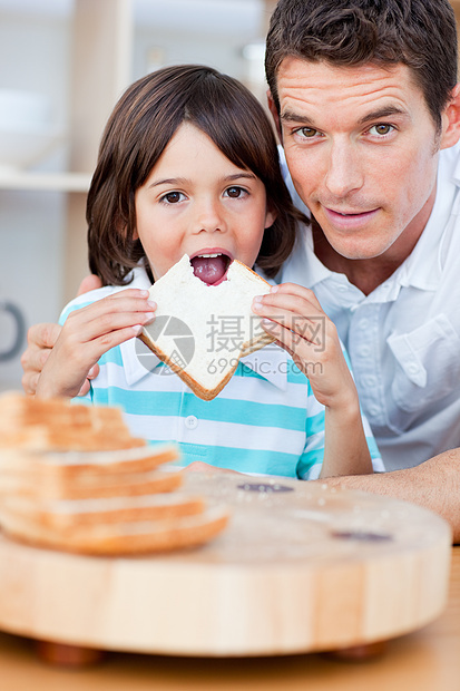 可爱的小男孩和他父亲在吃面包男人饥饿营养牛奶厨房男生女孩男性女性儿子图片