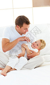 动动的爸爸和他的小男孩在床上玩图片
