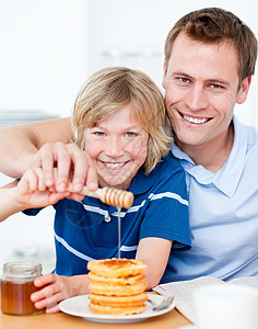 快乐男孩和他父亲在华夫饼上加蜂蜜图片