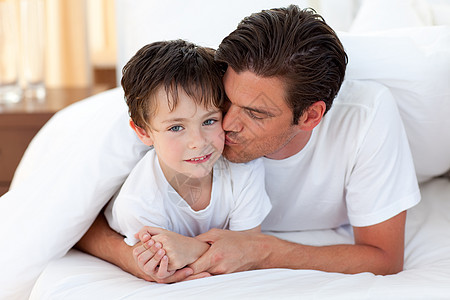 父亲亲吻他儿子躺在床上图片