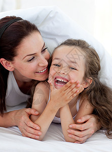 小女孩和她妈妈在床上玩得开心图片