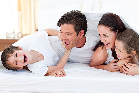 幸福的一家人躺在床上玩乐男性女孩乐趣男生父亲喜悦女士母亲女儿爸爸图片
