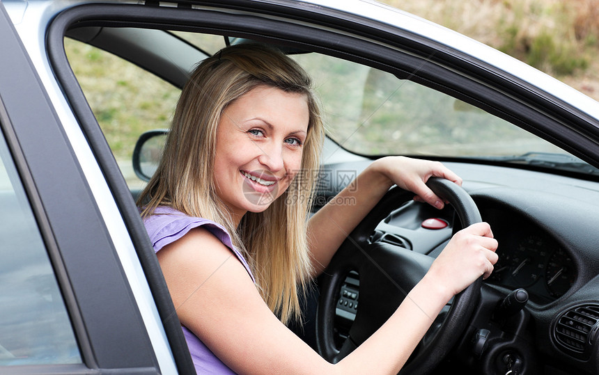 坐在车里的车轮上快乐的女司机幸福微笑青少年驾驶金发女郎金发汽车发动机女士开车图片
