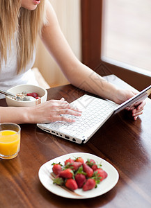 金发女人在吃早餐时用笔记本电脑图片