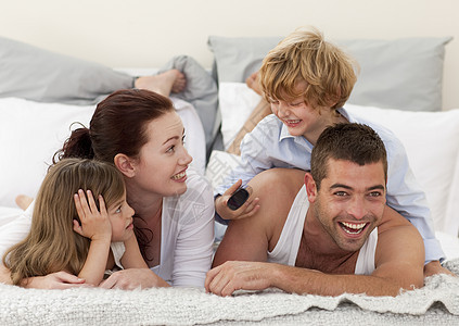 家庭躺在床上 儿子用遥控器图片