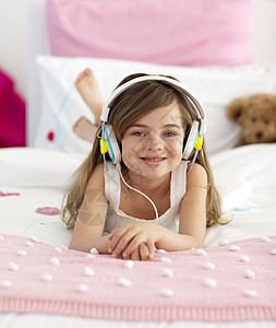 微笑的姑娘在床上听音乐图片