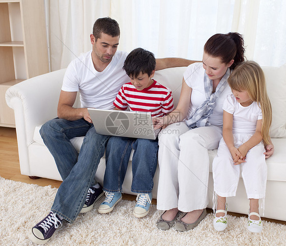 家庭使用笔记本电脑的家庭男生夫妻房间长椅互联网兄弟头发孩子金发微笑图片