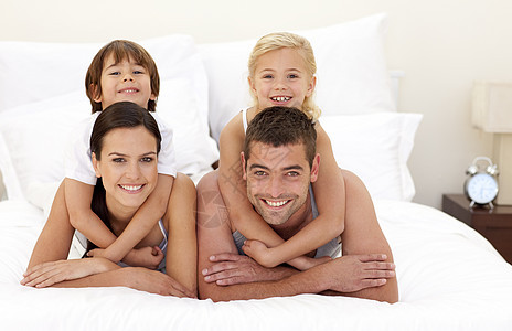 家庭在父母床上玩乐说谎感情乐趣女孩妈妈女士男人拥抱儿子男性图片
