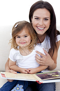 母亲和女儿在读一本书时微笑图片