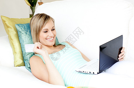 躺在沙发上在线购物的欢乐女人图片
